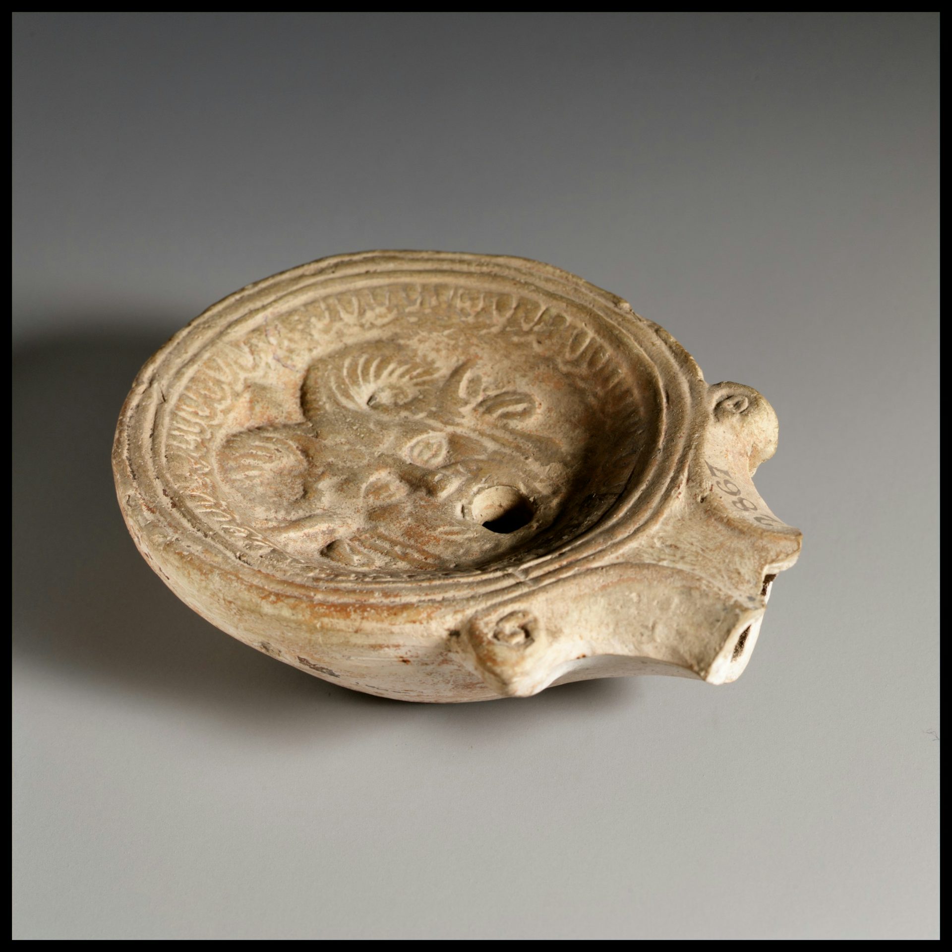 Terracotta oil lamp with relief of a mask of Pan