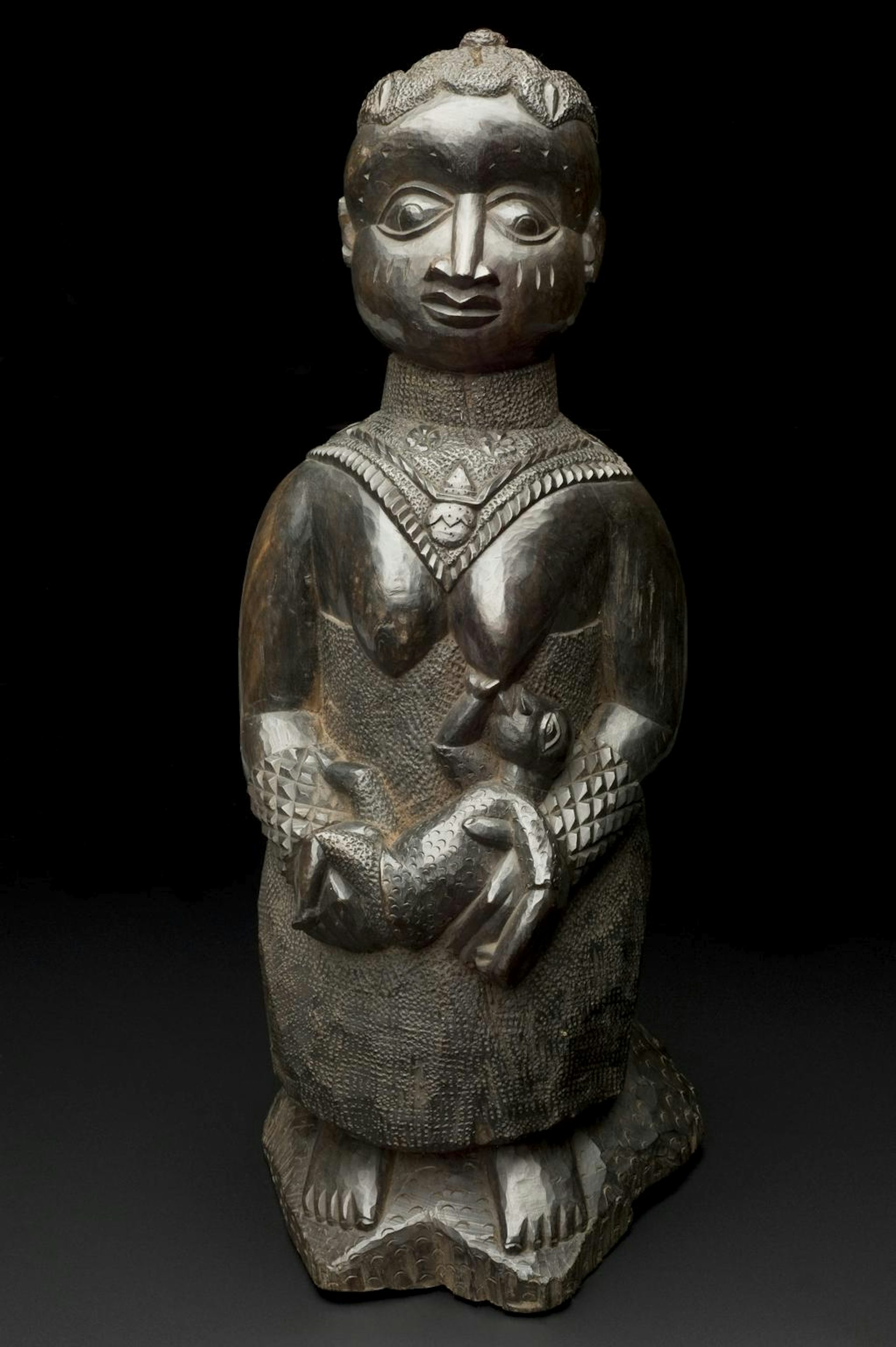 Carved breast-feeding woman by Yoruba artist (1890-1920).